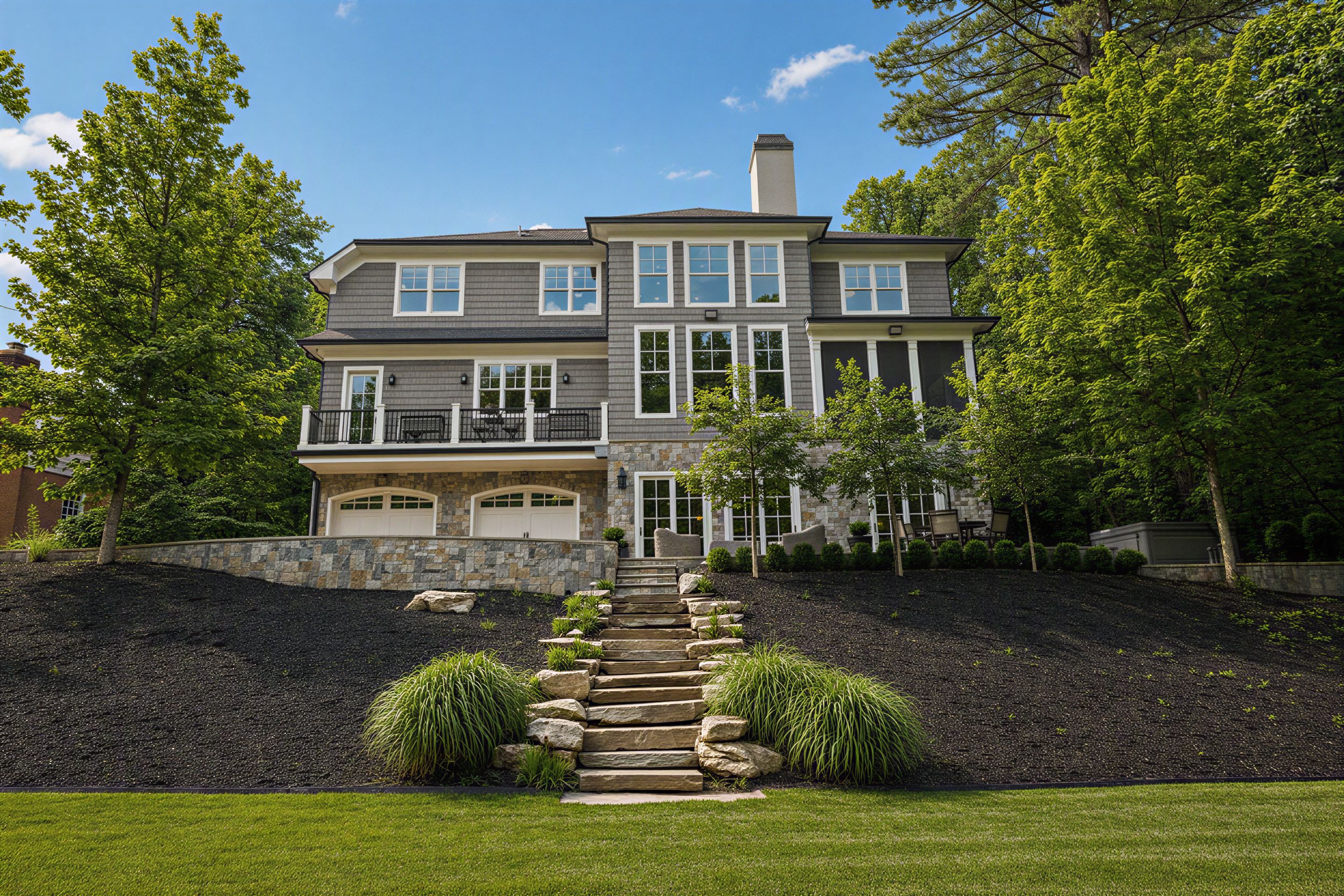 Side elevation of a luxury home with landscaped stone steps and mature trees