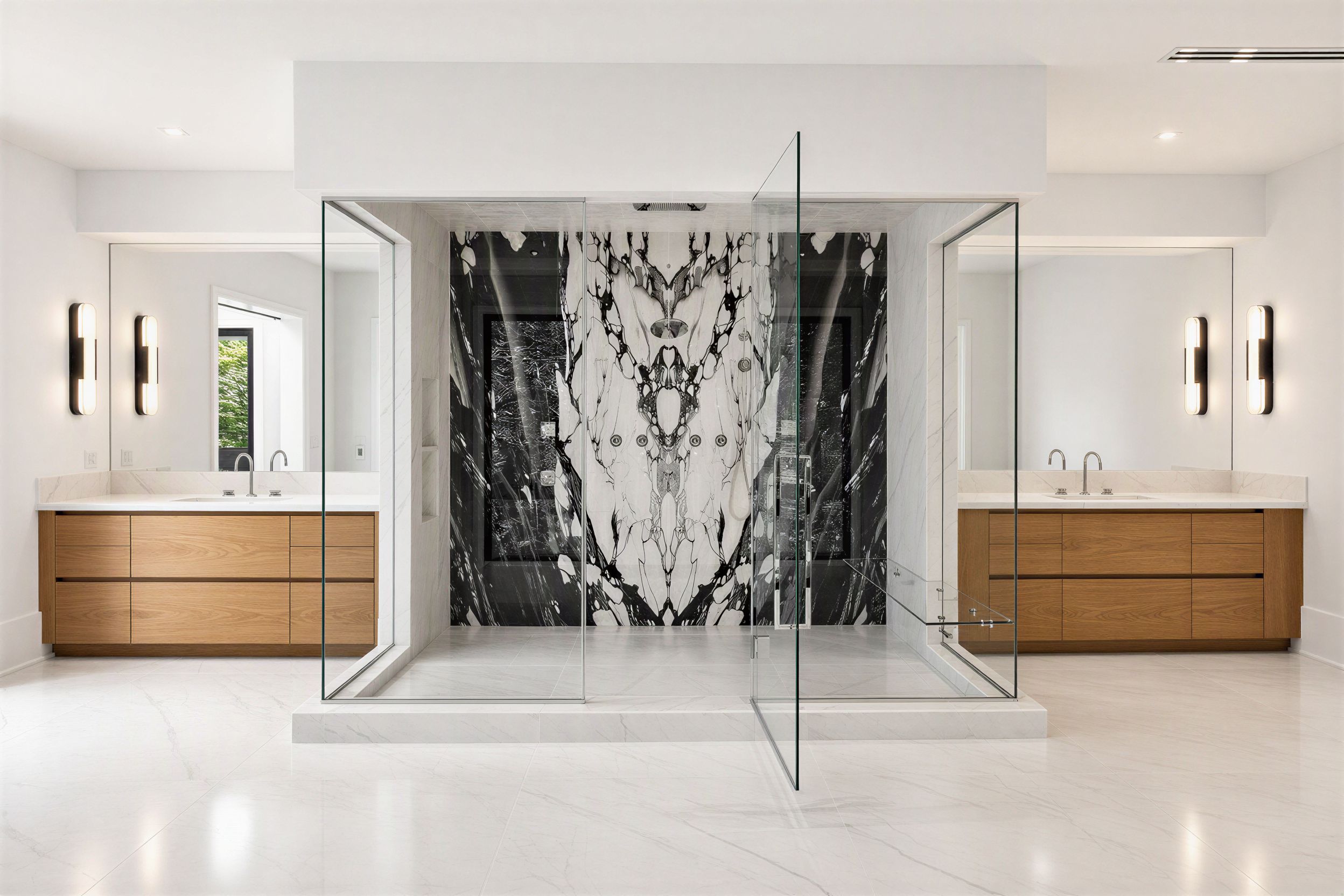 Luxury bath with a bookmatched black-and-white marble shower feature and dual vanities