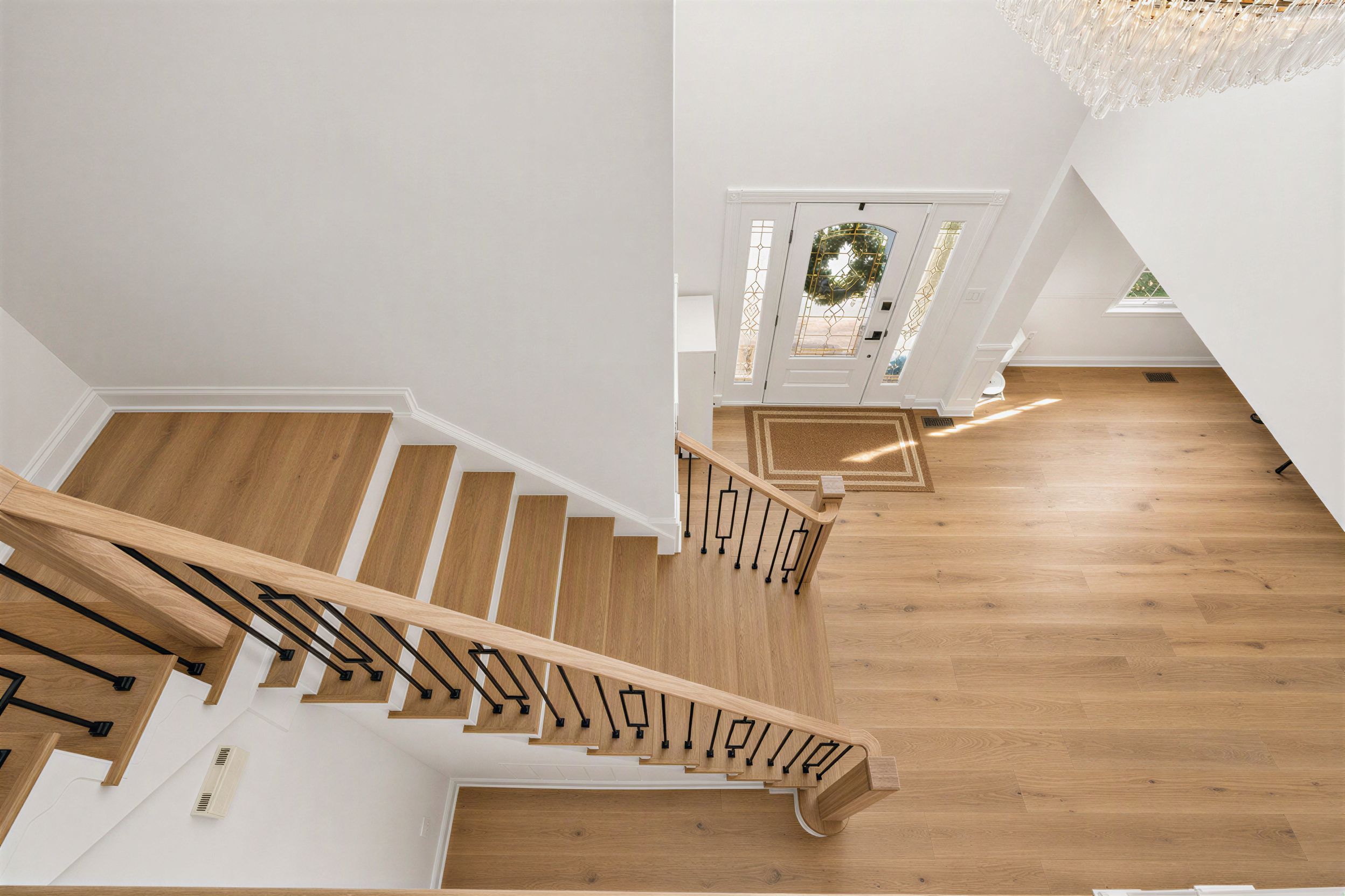 Overhead view of a floating light-wood staircase with sculptural black iron railings