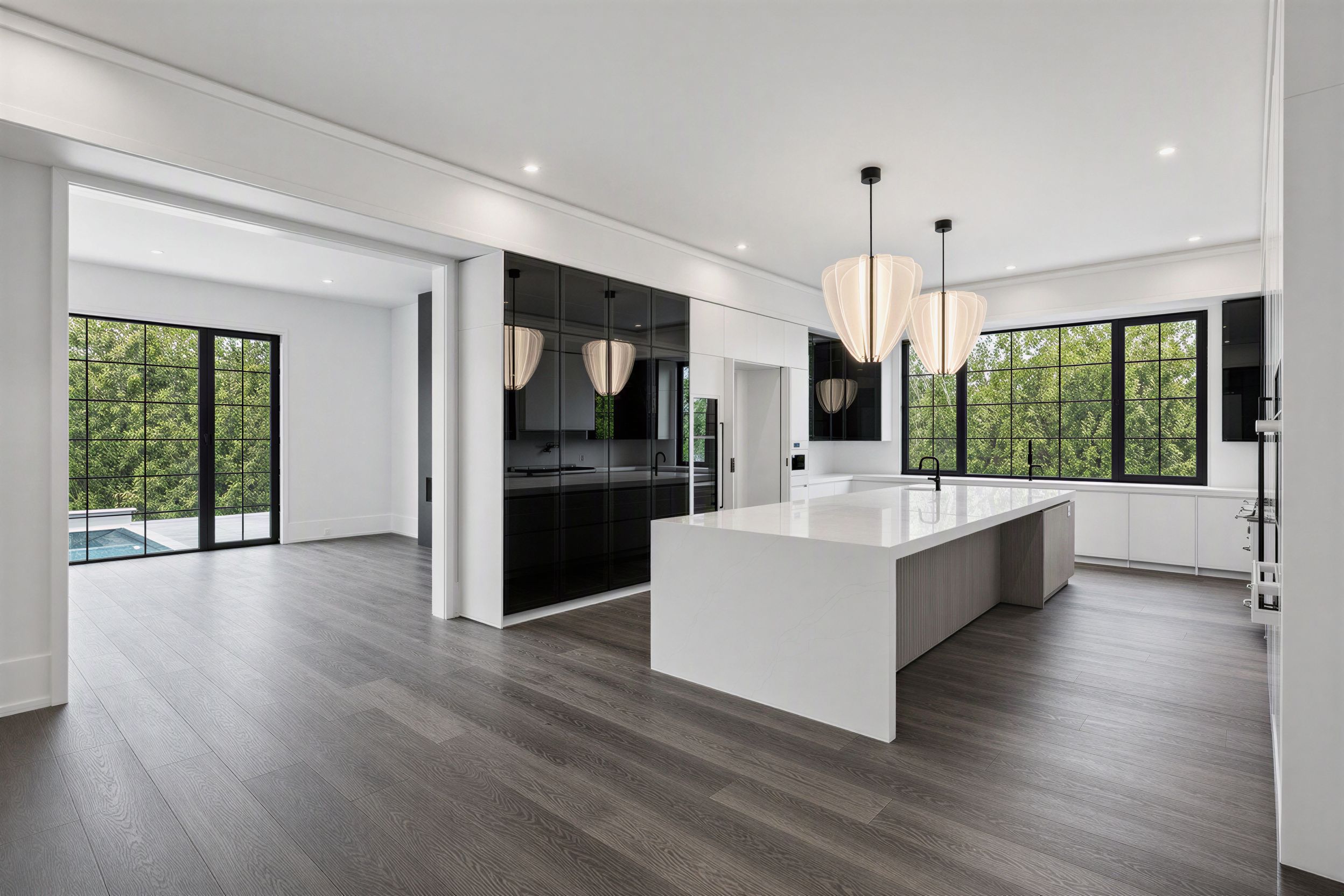 Dramatic black-and-white open great room with a white waterfall island and pool view